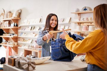 Boutique saleswoman handing item to customer