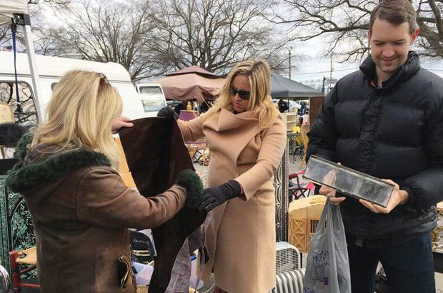 Shoppers inspecting coat at outdoor flea market