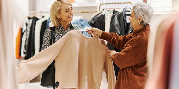 Two women shopping, holding beige sweater